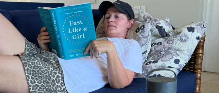 Fuchsmunter mit „Fast Like a Girl“ – Dr. Mindy Pelz Fuchsmunter liegt entspannt auf dem Sofa und liest „Fast Like a Girl“ von Dr. Mindy Pelz – zyklusbasiertes Fasten für Frauen.