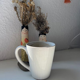 Ein Tässchen Kaffee am Morgen Weiße Tasse auf einem Tisch, dahinter zwei bemalte Vasen mit Trockenblumen.