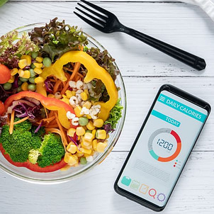 Kalorien sind alles – warum dieser Denkfehler ab 40 nicht stimmt Schüssel mit Salat neben Smartphone mit Kalorien-App – Symbol für den Denkfehler „Kalorien sind alles“ beim Abnehmen ab 40