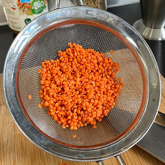 Rote Linsen für die Kürbis Linsen Suppe Rote Linsen in einem Metallsieb – Basis für die Kürbis Linsen Suppe, ein leichtes und sättigendes Rezept zum Kurzzeitfasten