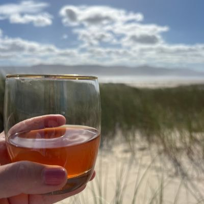 In_12_Tagen_zu_mehr_Leichtigkeit_dea_on_the_beach Ein Glas gefuellt mit Ringana dea am Beach der Sandown Bay bei Meerenbosch